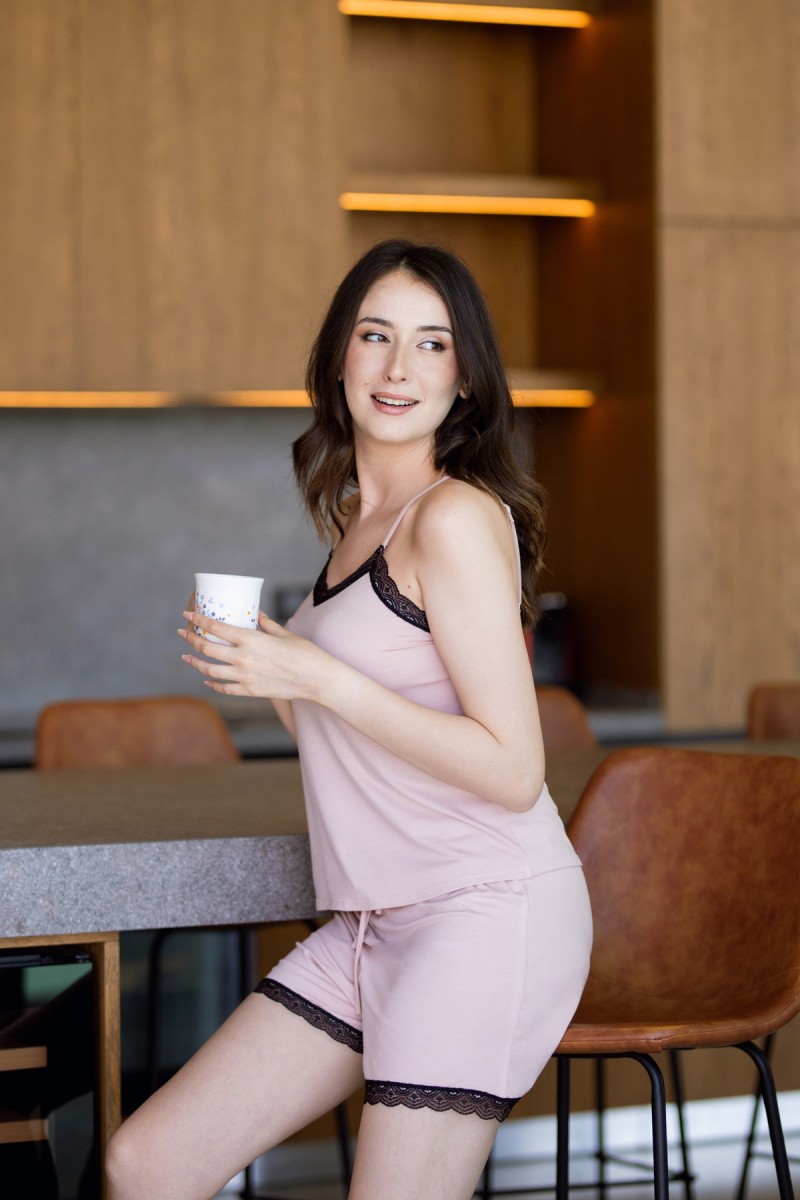 Femme portant un pyjama caraco et short en coton rose avec dentelle noire