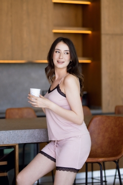 Femme portant un pyjama caraco et short en coton rose avec dentelle noire