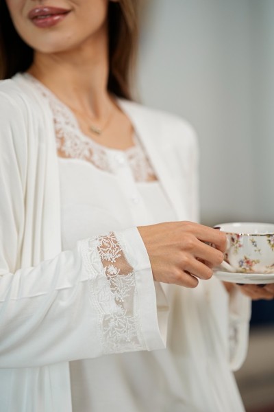 Gros plan sur la dentelle du kimono maternité ivoire Glossy Envy et la robe assortie.